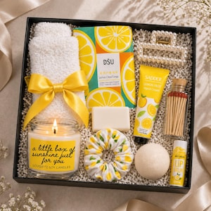 Peut inclure: Coffret cadeau sur le thème du citron. Il contient une bougie avec texte, une serviette blanche avec un nœud jaune, un chouchou, du savon, une crème pour les mains, des allumettes et un baume à lèvres. Le coffret est noir.