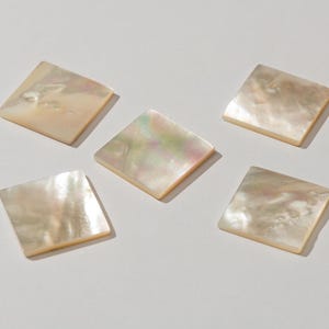 May include: Five iridescent white mother of pearl tiles in a square shape.
