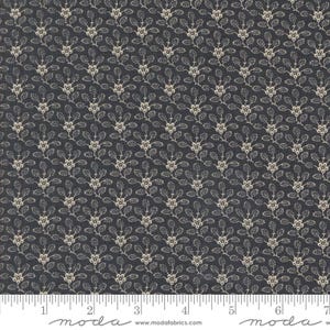 May include: Dark blue fabric with a repeating pattern of off-white floral sprigs. The sprigs have small, round berries and delicate leaves. A ruler is along the bottom edge, with the word "moda" printed on it.