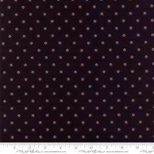 Op de afbeelding: Donkere stof met een herhalend patroon van kleine, vierkante ontwerpen. Elk vierkant heeft een rood midden en is omgeven door een donkerdere omtrek. Een liniaal is zichtbaar langs de onderkant van de stof.