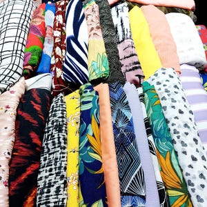 Peut inclure: Un assortiment d'échantillons de tissus colorés avec différents motifs, notamment floraux, géométriques et abstraits. Les tissus sont enroulés et disposés en rangée.