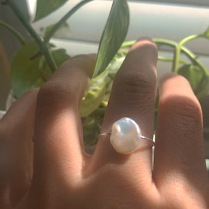 May include: A silver ring with a large, white, baroque pearl.