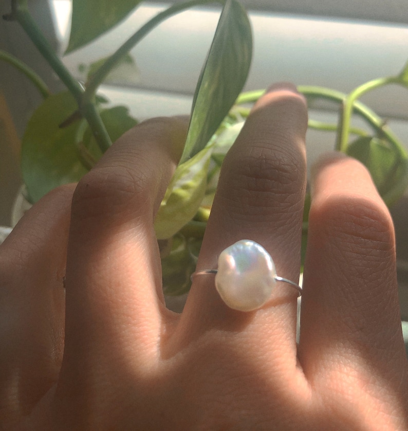 May include: A silver ring with a large, white, baroque pearl.
