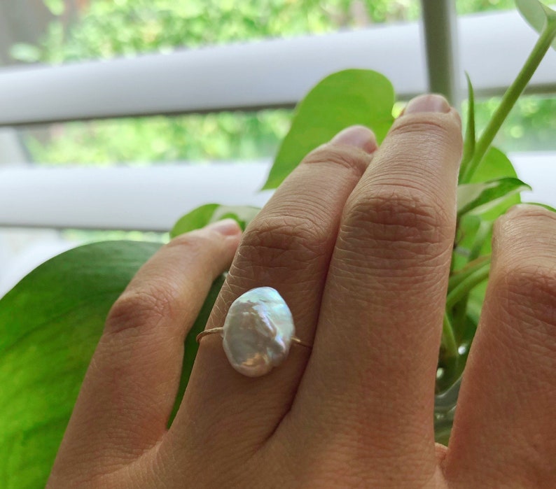 May include: A gold ring with a large, white, irregular-shaped pearl.