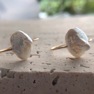 May include: A pair of gold earrings with white baroque pearl accents.