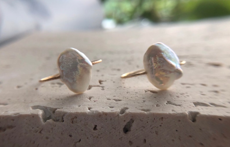 May include: A pair of gold earrings with white baroque pearl accents.