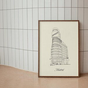 May include: A framed black and white line drawing of a building in Madrid, Spain. The building has a sign that says "Schweppes". The drawing is on a cream-colored background with the word "Madrid" printed at the bottom.