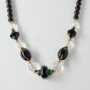 May include: A black and iridescent glass beaded necklace with clear glass beads and gold accents.