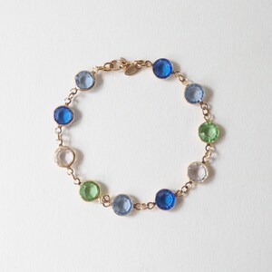 K&ouml;nnte beinhalten: Ein goldenes Kettenarmband mit blauen, gr&uuml;nen und klaren runden Edelsteinen.