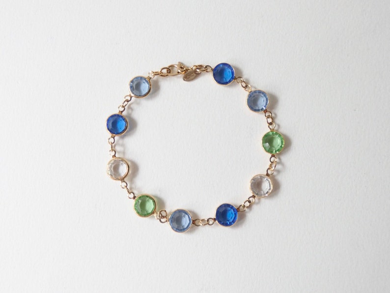 K&ouml;nnte beinhalten: Ein goldenes Kettenarmband mit blauen, gr&uuml;nen und klaren runden Edelsteinen.