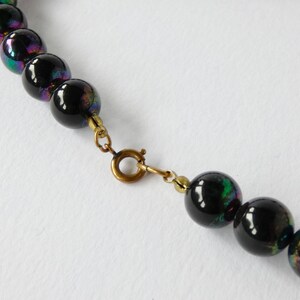 May include: A black iridescent glass bead necklace with a gold clasp.