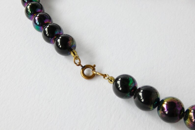 May include: A black iridescent glass bead necklace with a gold clasp.