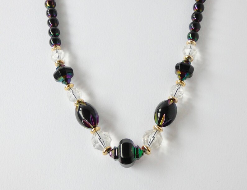 May include: A black and iridescent glass beaded necklace with clear glass beads and gold accents.