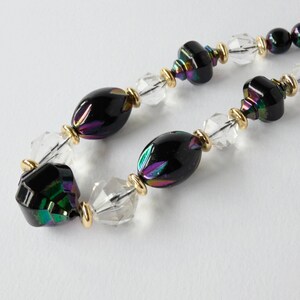 May include: A black and iridescent glass bead necklace with clear crystal beads and gold accents.