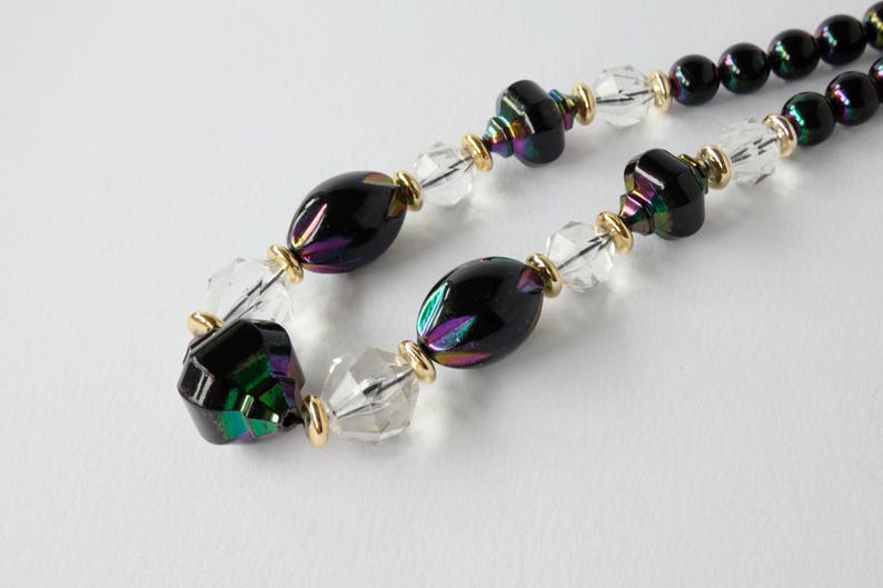 May include: A black and iridescent glass bead necklace with clear crystal beads and gold accents.