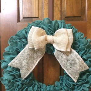 May include: Teal burlap wreath with a large white burlap bow. The wreath is made of ruched burlap and is perfect for a farmhouse or rustic decor style.