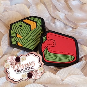 May include: Two green and red cartoon patches, one depicting a stack of money and the other a wallet. The patches are on a white background with a pink and white floral logo that reads "Kimmie's Kreationz Gifts For Every Occasion."