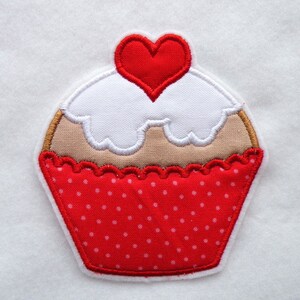 May include: Red and white cupcake with a red heart on top. The cupcake has a red and white polka dot pattern.