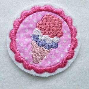 Könnte beinhalten: Ein gestickter Eiswaffel-Aufnäher in Rosa und Weiß mit einem gewellten Rand.