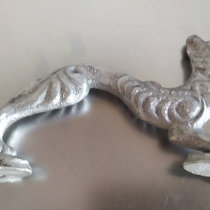 May include: A silver metal door handle shaped like a stylized animal, possibly a dog or a wolf, with intricate details and a textured surface.