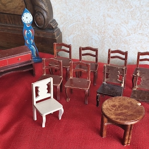 May include: A collection of miniature wooden furniture, including chairs, a table, and a dresser with red accents. A blue and white decorative clock is also present. The items are arranged on a red surface.