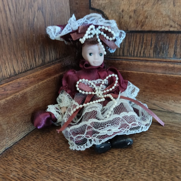 Vintage Kollektion Feines Porzellan Puppe 18 cm hoch schwarzes lockiges Haar / Bordo Kleid schönes Mädchen Sammlerstück authentisch (sitzende Porzellanpuppe)
