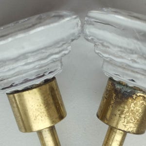 Puede incluir: Dos pomos de puerta de vidrio transparente con una superficie texturizada y bases de latón.