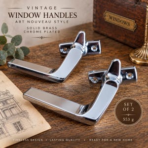 Op de afbeelding: Twee verchroomde raamkrukken van massief messing met een reflecterende afwerking. De set van twee weegt 553 g. De tekst op de afbeelding luidt: VINTAGE WINDOW HANDLES ART NOUVEAU STYLE SOLID BRASS CHROME PLATED, SET OF 2 553 g, TIMELESS DESIGN LASTING QUALITY READY FOR A NEW HOME.