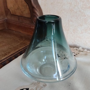 May include: A clear glass vase with a dark blue ombre effect. The vase has a wide base and a narrow opening.