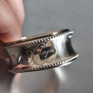 Peut inclure: Une tasse en céramique blanche avec une anse noire et l'inscription "But First, Coffee" en gras noir. La tasse est posée sur un fond flou, suggérant un cadre chaleureux.