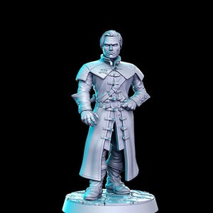 Puede incluir: Una figurita miniatura pintada de gris de un hombre que lleva un abrigo largo con hebillas y una expresión seria. La figurita está de pie sobre una base redonda.