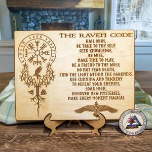 Może przedstawiać: Drewniany znak z wygrawerowanym kodem kruka. Znak przedstawia kompas, drzewo i kruka. Tekst na znaku brzmi: "The Raven Code. Hail Odin, Be true to thy self, Seek knowledge, Be wise, Make time to play, Be a friend to the wolf, Do not fear death, Find the light within the darkness, Use cunning and trickery to defeat your enemies, Soar high, Discover new mysteries, Make every moment magikal."