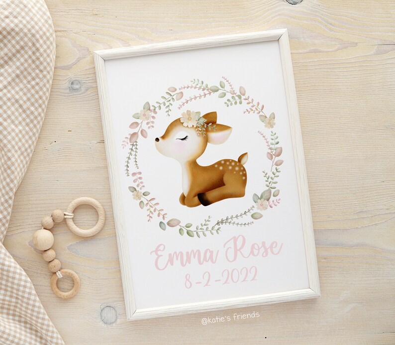 Pu&ograve; includere: Una stampa incorniciata bianca con un'illustrazione ad acquerello di un cerbiatto con gli occhi chiusi circondato da una ghirlanda di fiori. Il testo "Emma Rose 8-2-2022 @katie's friends" &egrave; stampato sotto il cerbiatto.
