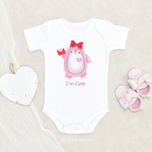 Op de afbeelding: Witte baby romper met een roze pingu&iuml;n die een rode envelop vasthoudt en een rode strik draagt. De pingu&iuml;n heeft een klein roze hart op zijn borst. De tekst "I'm Cute" is onder de pingu&iuml;n gedrukt.