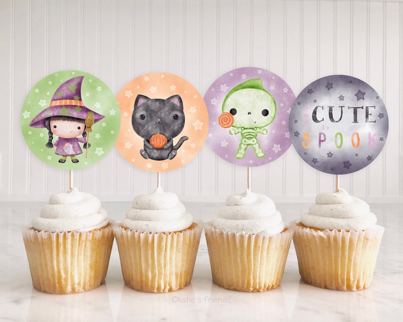 May include: Four cupcake toppers featuring cute Halloween characters. The toppers are printed on round circles with a green witch, a black cat, a green skeleton, and a purple and gray circle with the text "Cute to Spook".