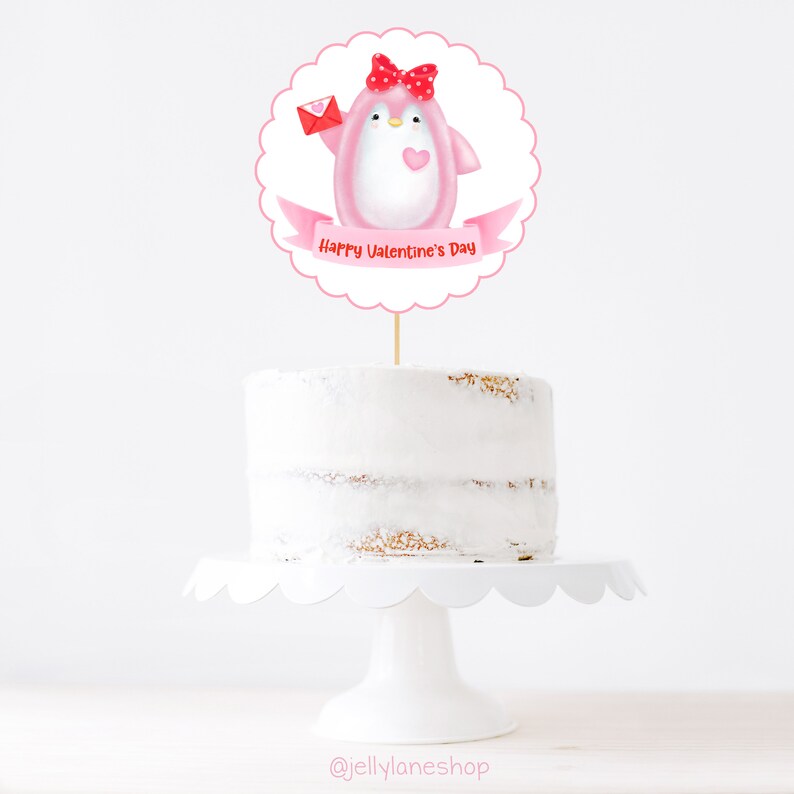 Op de afbeelding: Roze pingu&iuml;n taarttopper met een rode strik en een rode envelop. De topper zegt "Happy Valentine's Day".