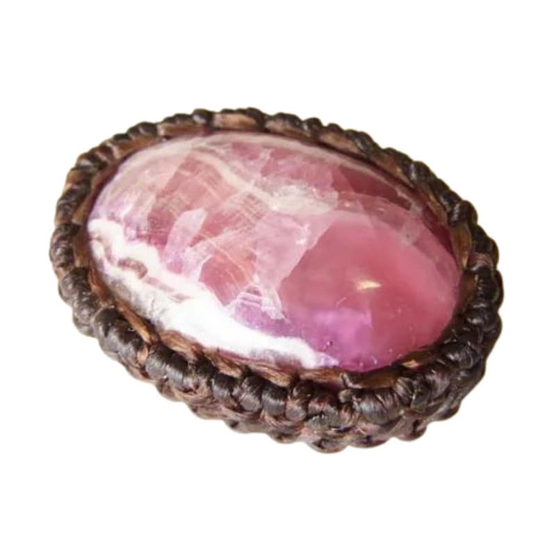 May include: A pink and white gemstone set in a brown leather cord, with a braided design around the edge.