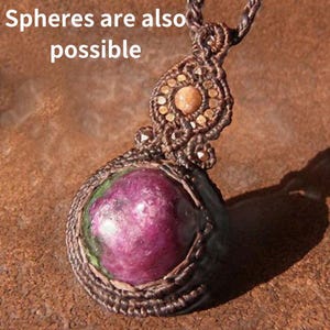 May include: A brown macrame necklace with a round, pink and green gemstone pendant. The pendant is surrounded by brown macrame and the text "Spheres are also possible" is visible in the background.