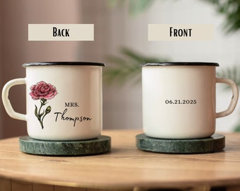 Puede incluir: Taza de esmalte blanco con borde y asa negros. La taza tiene un clavel rosa con hojas verdes en la parte posterior y el texto "MRS. Thompson" impreso debajo. La parte delantera de la taza tiene la fecha "06.21.2025" impresa.