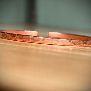 May include: A hammered copper bracelet with a smooth, polished finish.