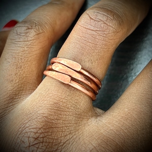 May include: A set of three copper rings, each with a hammered finish, worn on a finger.
