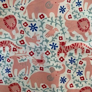 May include: White fabric with a repeating pattern of pink elephants, lions, tigers, deer, birds, and rabbits. The design includes red flowers, blue star-shaped flowers, and gray vines. The overall theme is a whimsical animal print.