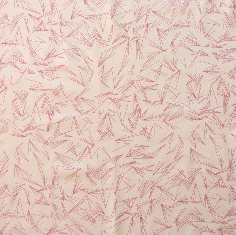 May include: A fabric with a repeating pattern of thin, pink lines arranged in a scattered, geometric design. The lines are of varying lengths and angles, creating a textured appearance against a light beige background. The overall effect is abstract and modern.