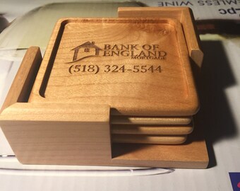 May include: Set of four wooden coasters with a logo for Bank of England Mortgage. The logo includes a house icon and the phone number (518) 324-5544.