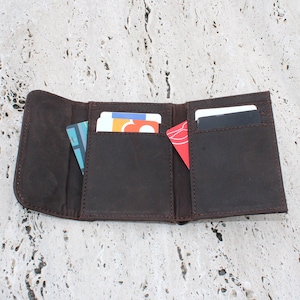 Cartera fina de cuero con tres compartimentos magnéticos para monedas, tarjetas y billetes.