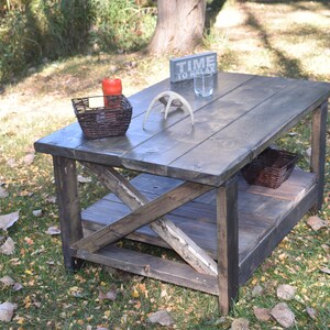 May include: A rustic wooden coffee table with a distressed gray finish. The table has a lower shelf and a sign that reads "Time to Relax".
