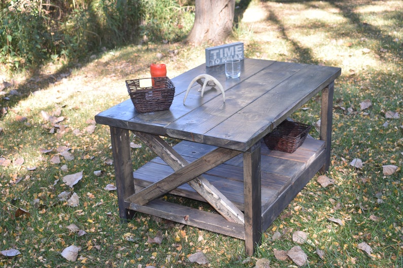 May include: A rustic wooden coffee table with a distressed gray finish. The table has a lower shelf and a sign that reads "Time to Relax".