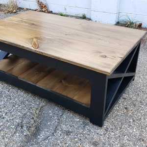 May include: A black coffee table with a wooden top and a lower shelf. The table has a geometric design on the front.