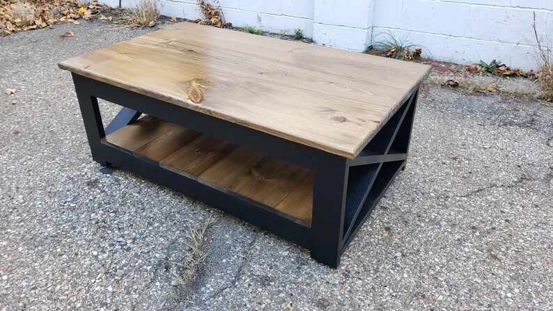 May include: A black coffee table with a wooden top and a lower shelf. The table has a geometric design on the front.