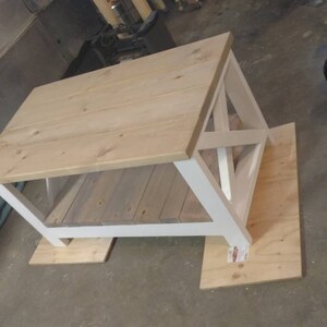 May include: White coffee table with a wooden top and a white base. The table is sitting on a wooden floor.